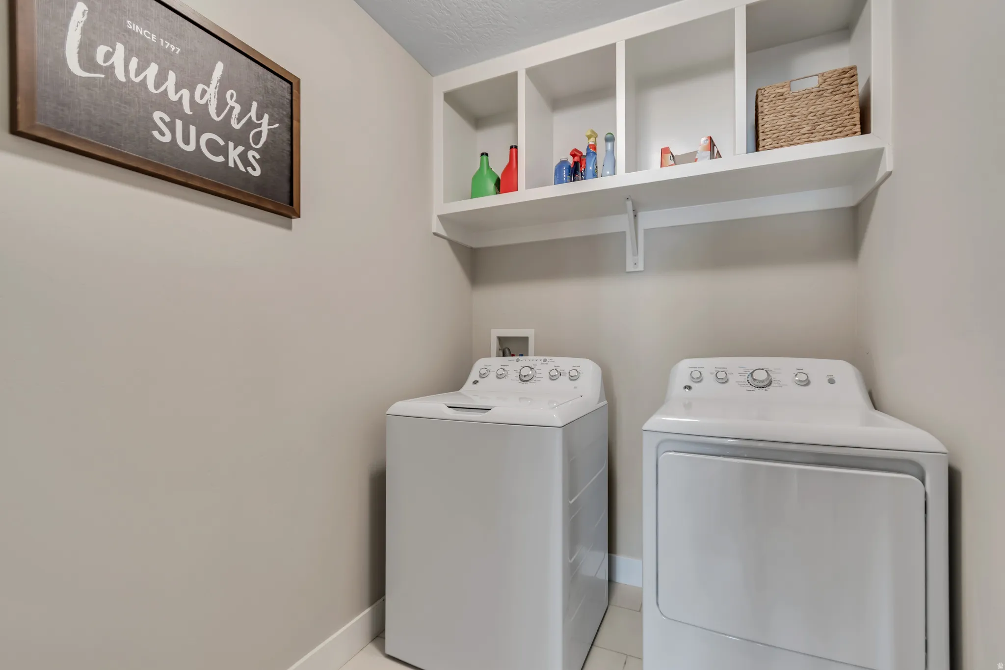 Laundry room with washing machine and clothes dryer and light tile patterned floors