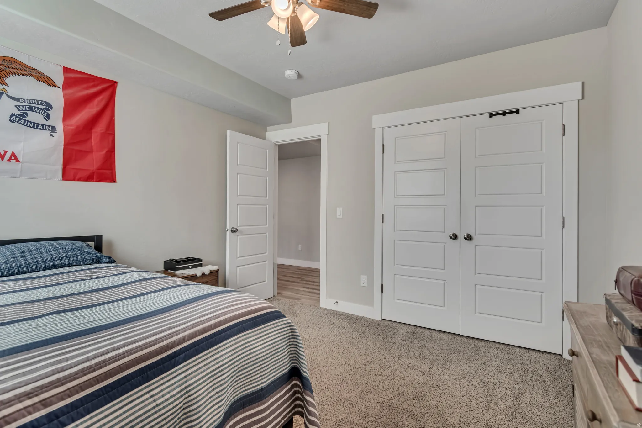 Bedroom with light colored carpet, ceiling fan, and a closet