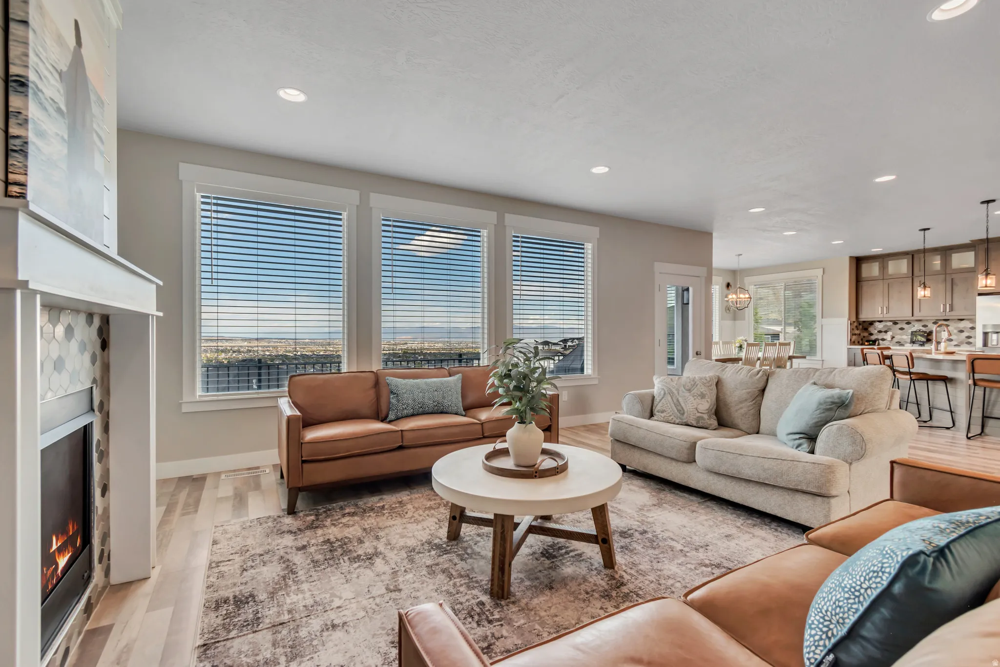 Living room featuring a warm lit fireplace, light wood finished floors, and recessed lighting