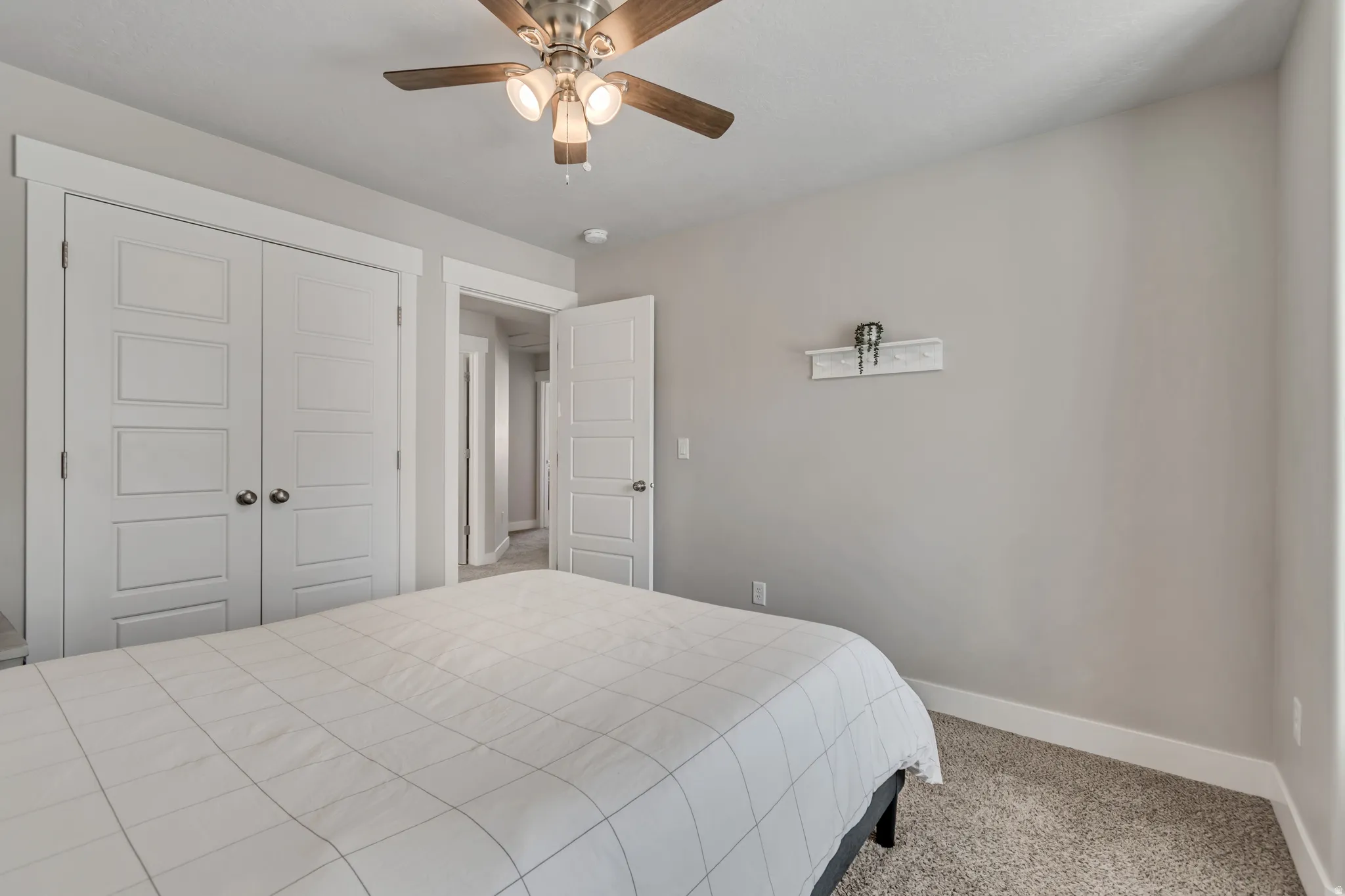 Bedroom with light colored carpet, ceiling fan, and a closet