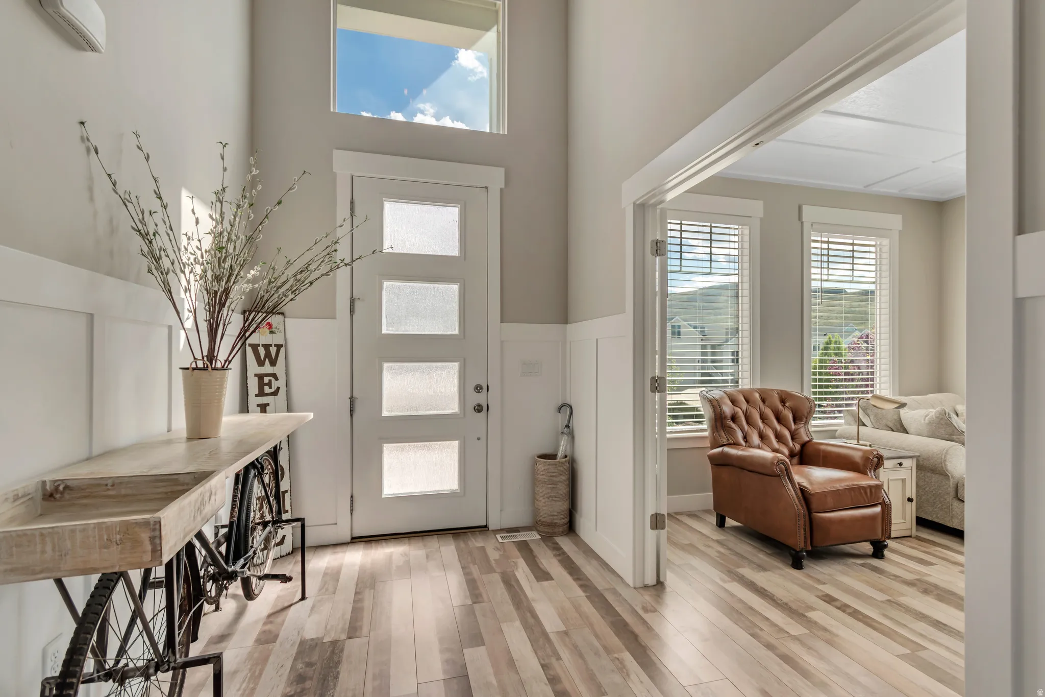 Foyer with light wood-style flooring, a high ceiling, and a wainscoted wall