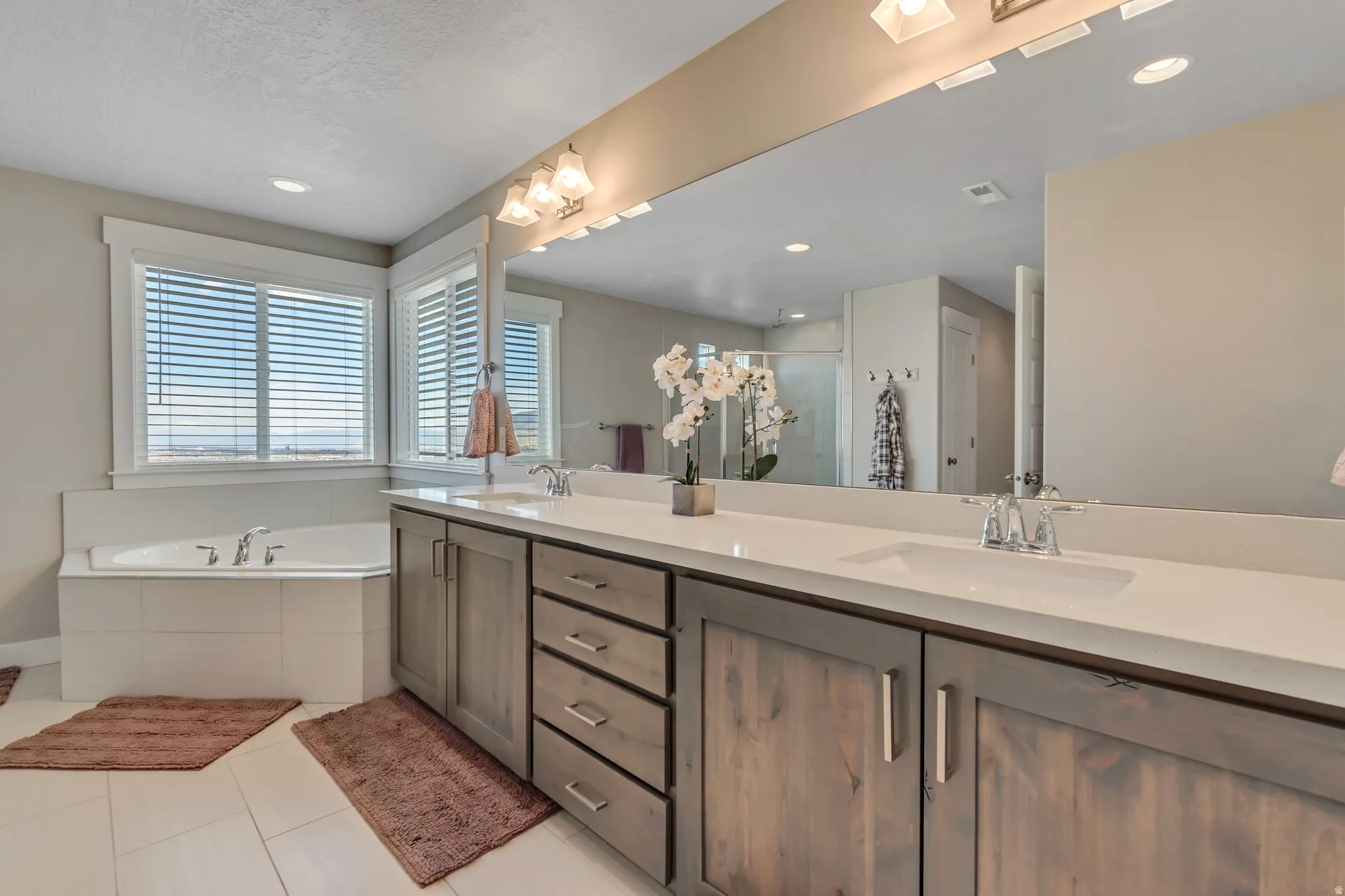 Bathroom featuring double vanity, a stall shower, a garden tub, light tile patterned floors, and recessed lighting