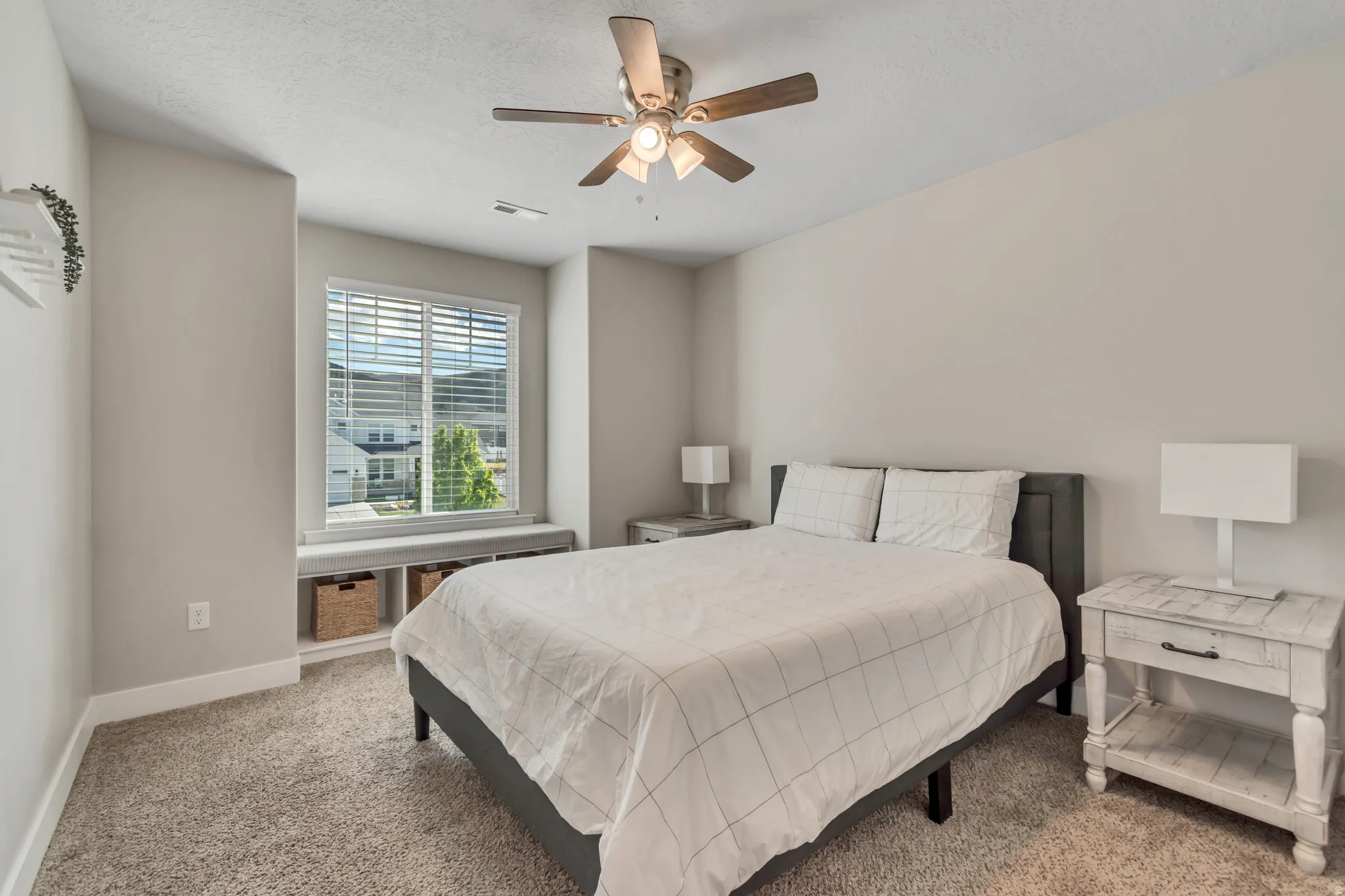 Carpeted bedroom with ceiling fan and a textured ceiling