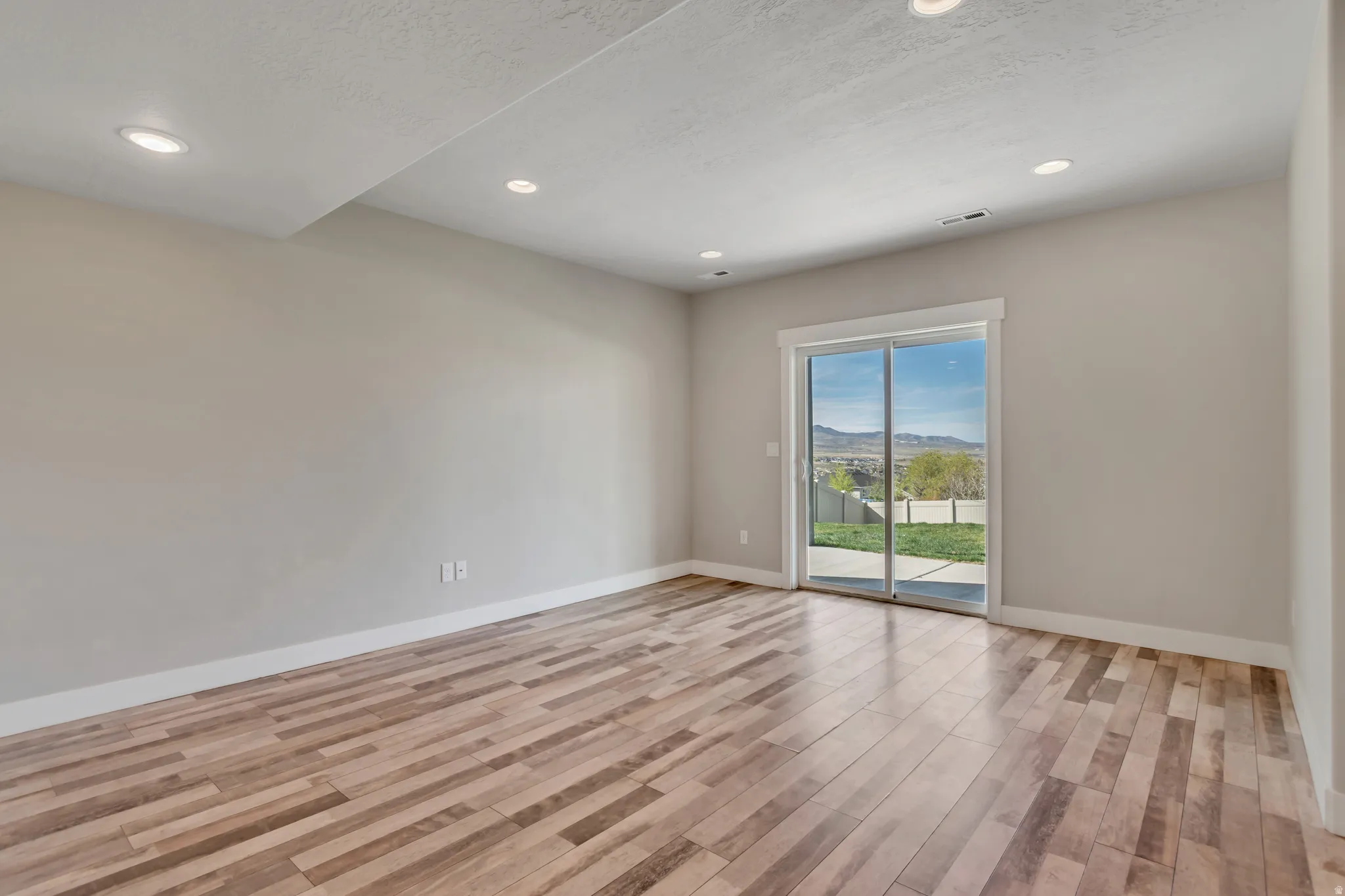 Spare room featuring a mountain view, light wood finished floors, recessed lighting, and a textured ceiling