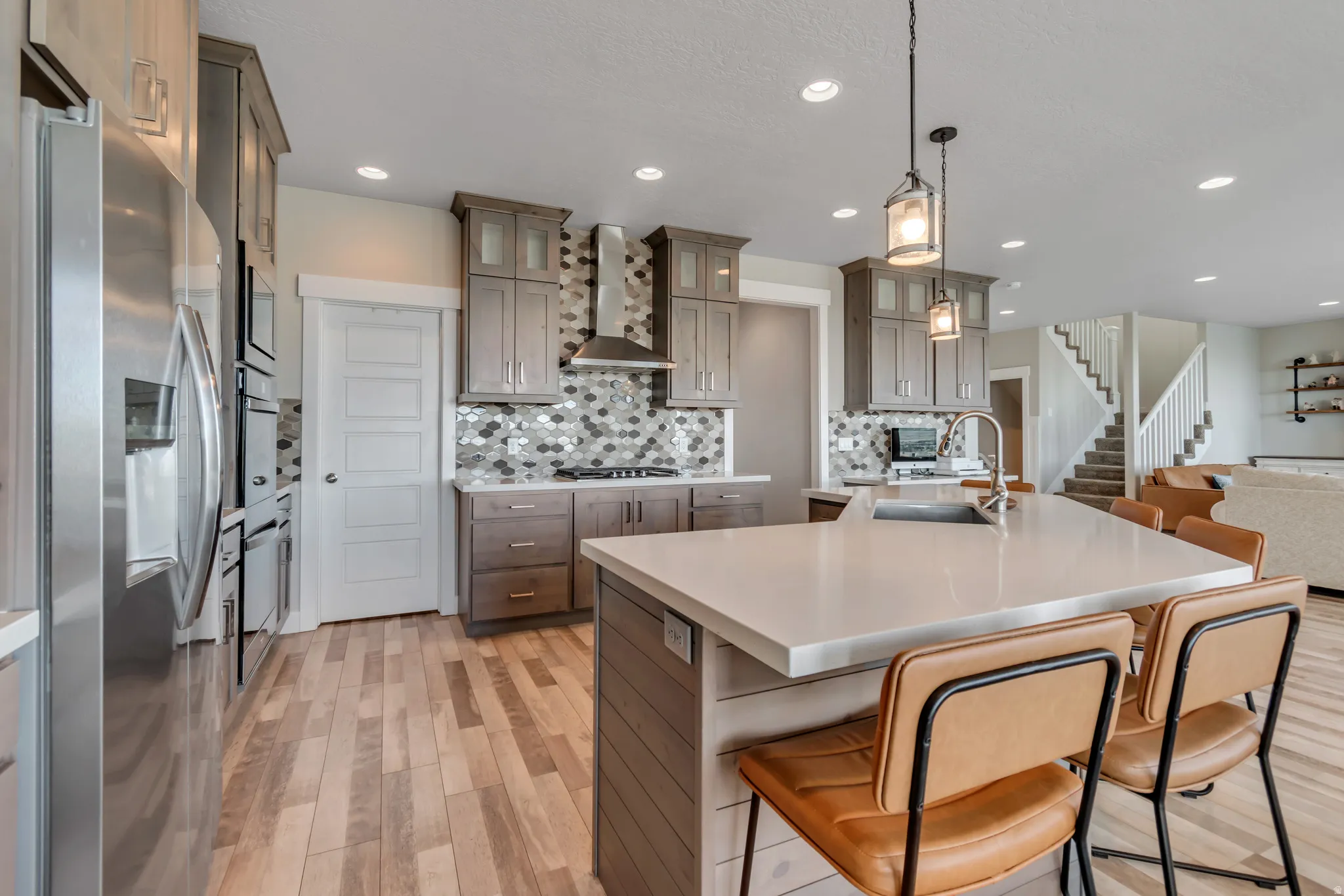 Kitchen featuring stainless steel appliances, light wood-type flooring, a large island, glass fronted cabinets, and a breakfast bar area