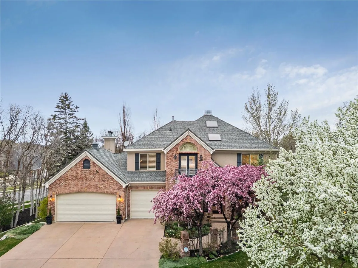 Traditional-style residence featuring a brick and stucco exterior, a gray shingled roof, and a two-car garage