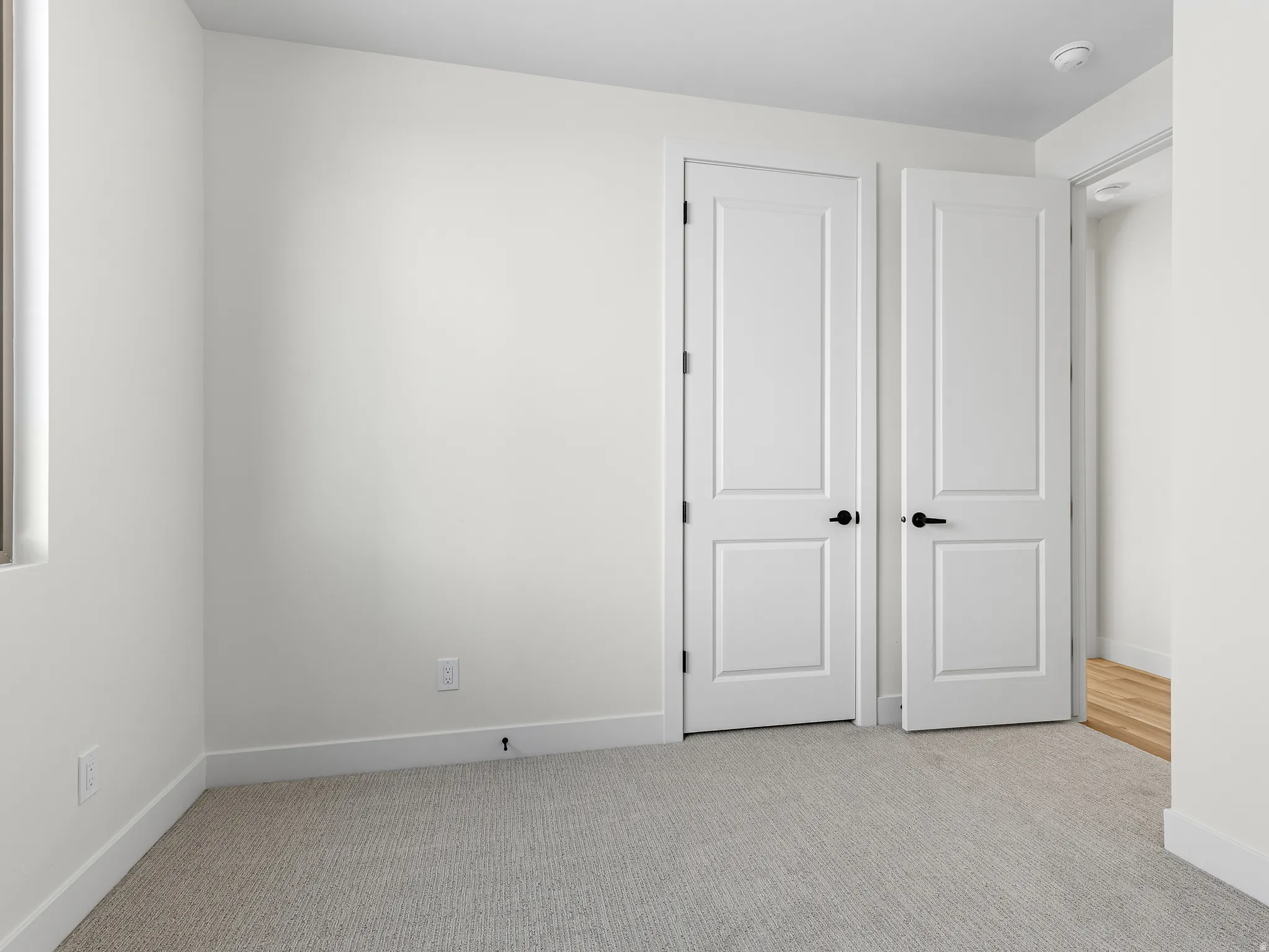 Unfurnished bedroom with light carpet and baseboards