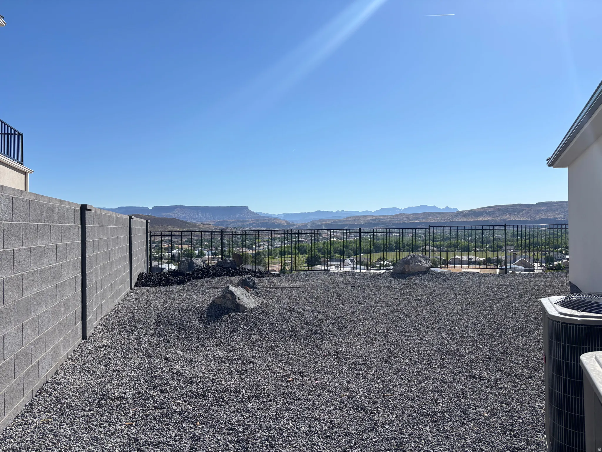 Expansive outdoor space featuring a gravel ground cover and a low-maintenance block wall