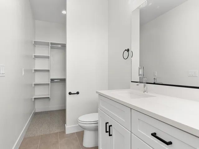 Bathroom featuring vanity, light tile patterned flooring, and a walk in closet