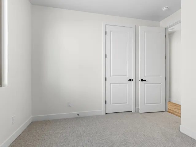 Unfurnished bedroom with light carpet and baseboards