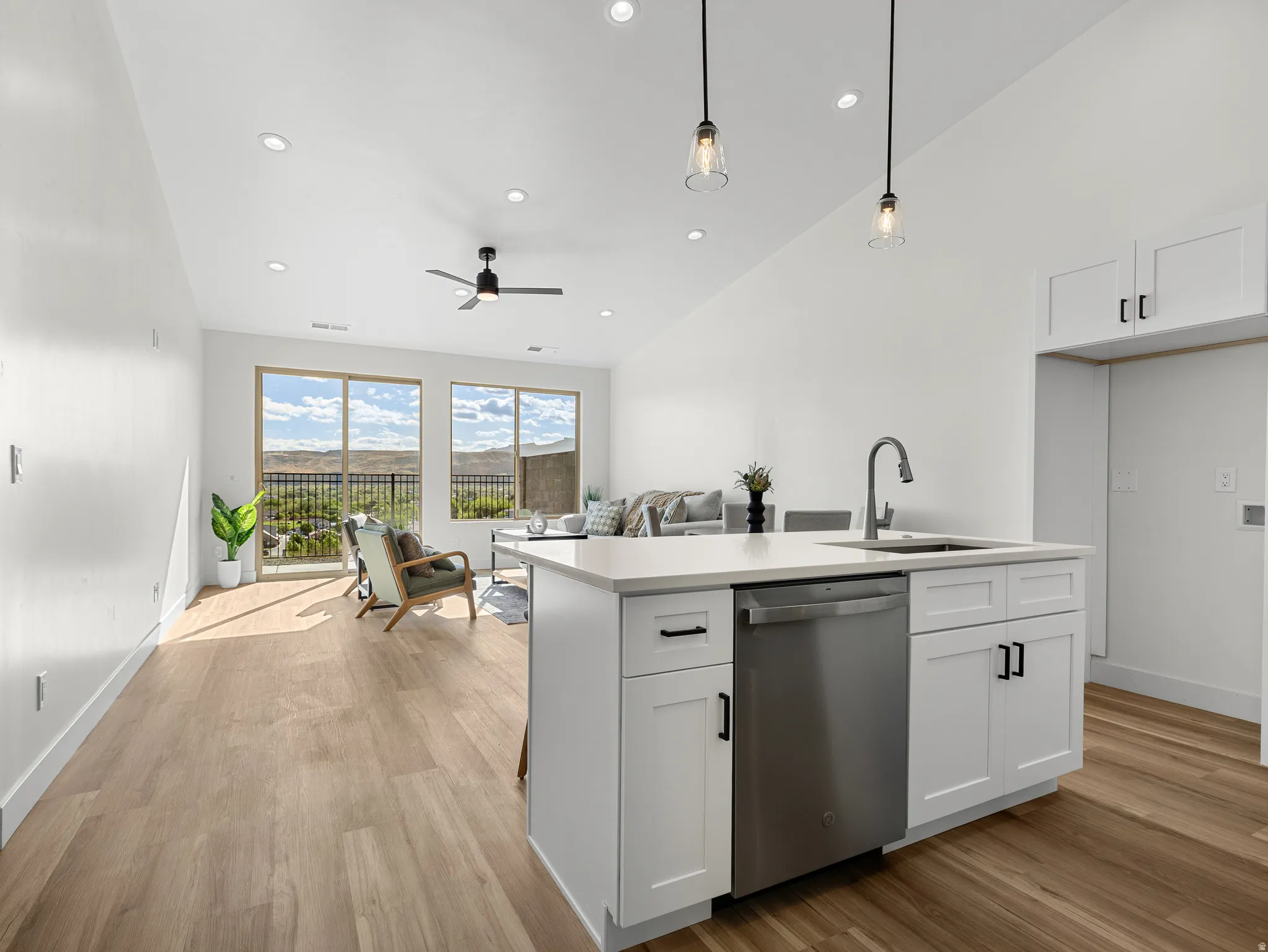 Kitchen featuring open floor plan, white cabinets, dishwasher, and light wood-type flooring