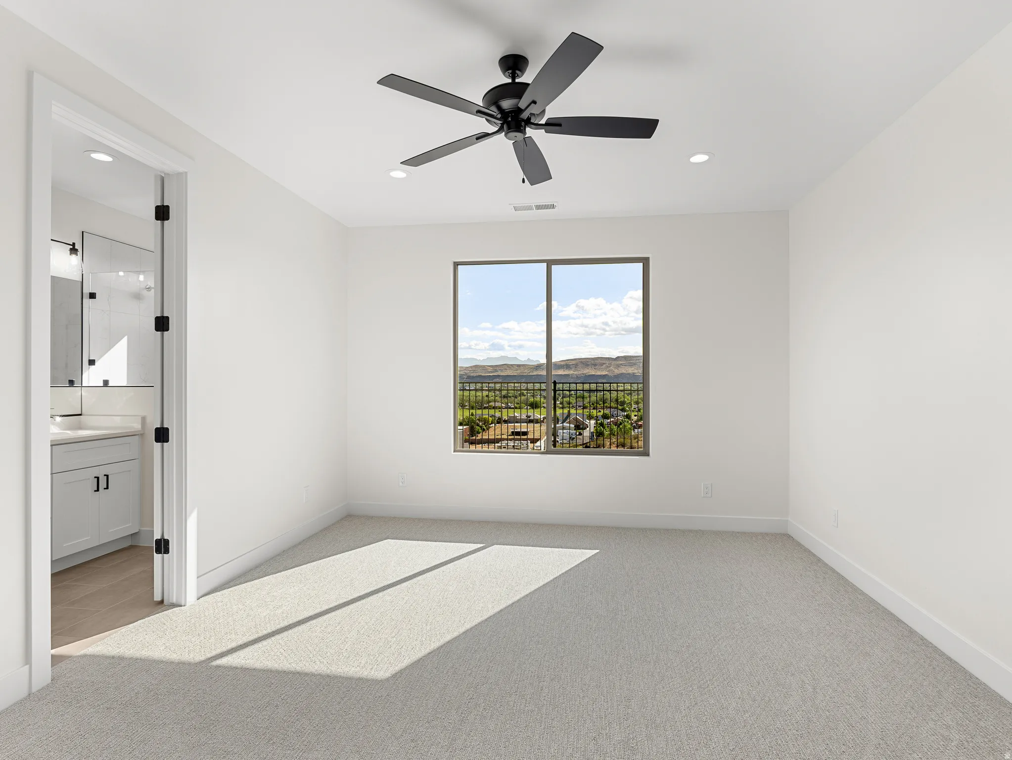 Unfurnished bedroom with light carpet, a ceiling fan, a mountain view, recessed lighting, and connected bathroom