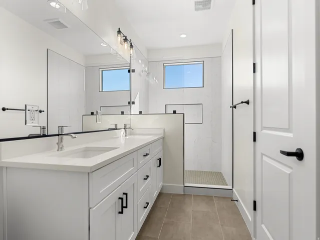 Full bathroom with double vanity, a marble finish shower, recessed lighting, and light tile patterned floors