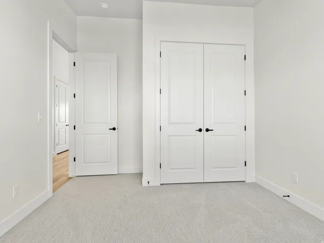 Unfurnished bedroom featuring light carpet and a closet