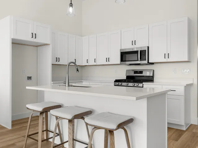 Kitchen with white cabinets, a breakfast bar area, stainless steel appliances, and light wood-style flooring