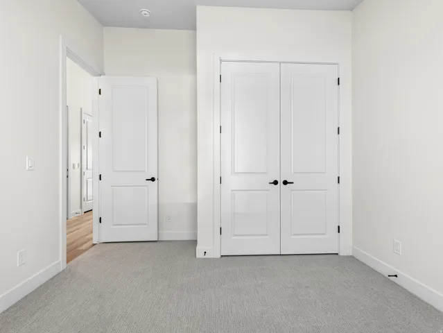 Unfurnished bedroom with light carpet and a closet
