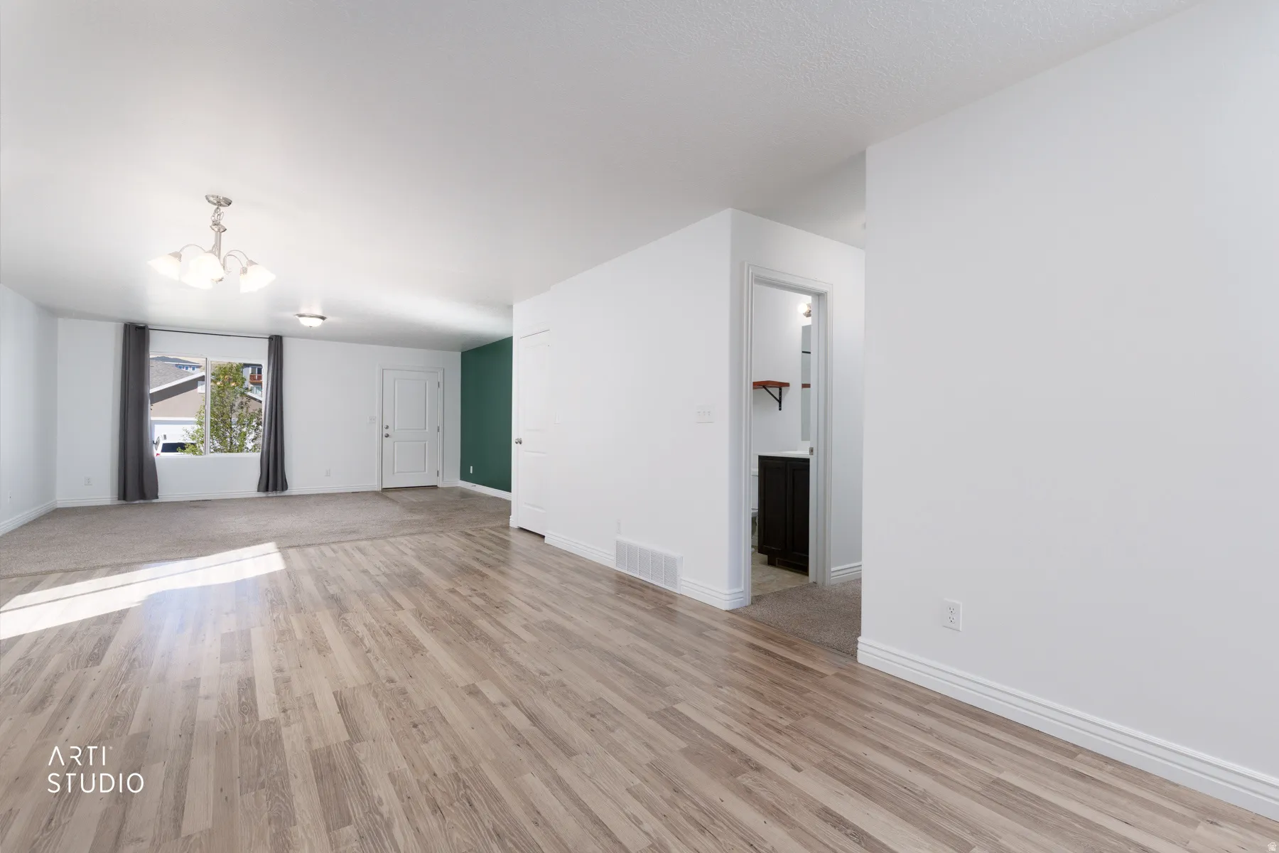Unfurnished living room with light wood-type flooring and hanging lights