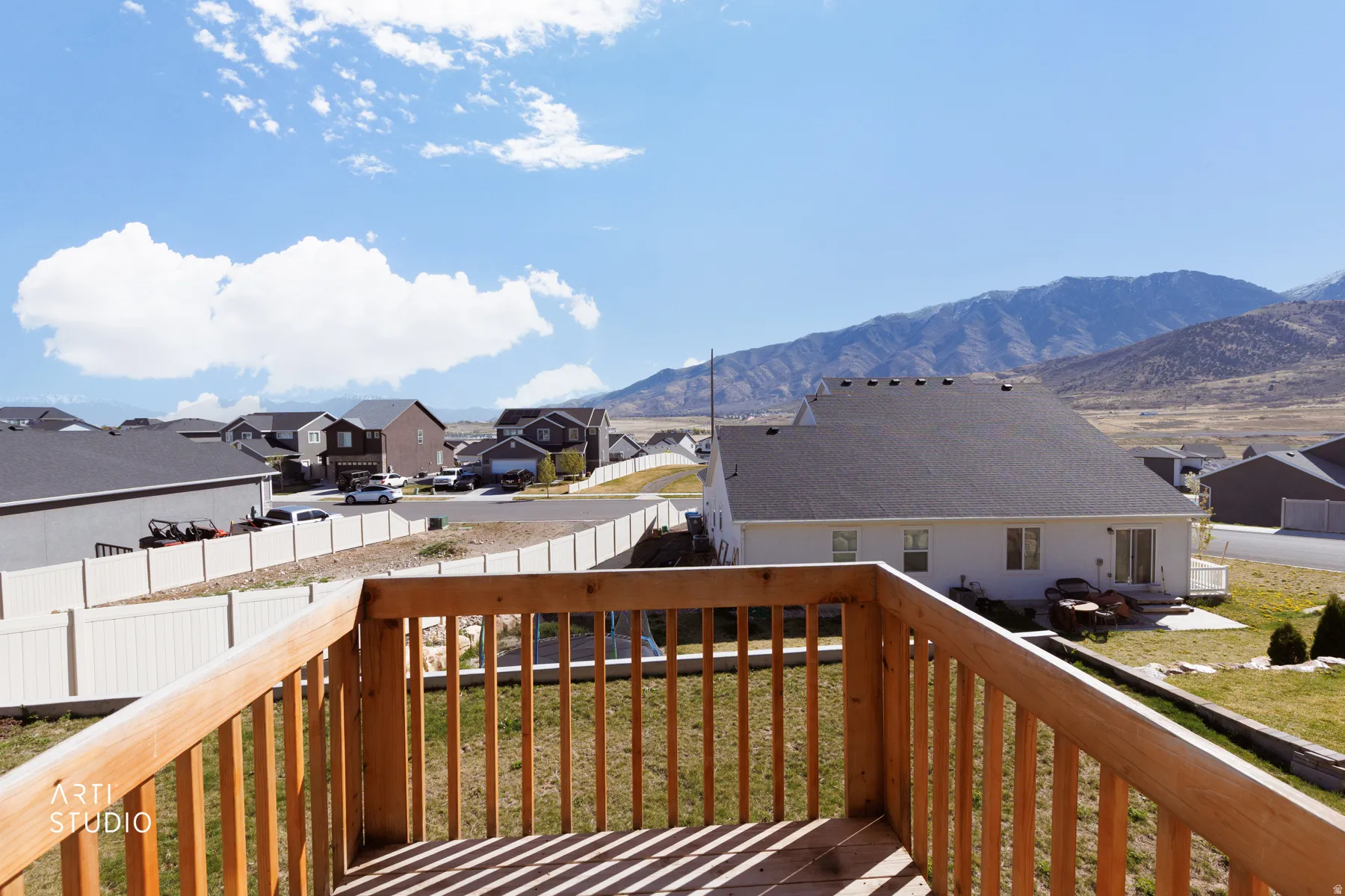 Wooden balcony featuring a residential view, a fenced backyard, and a mountain view