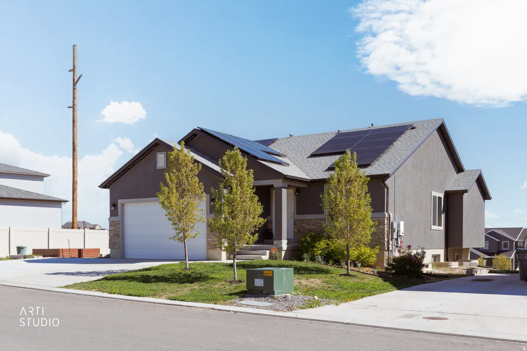 View of front of home with a front lawn, concrete driveway, an attached garage, roof with shingles, and solar panels