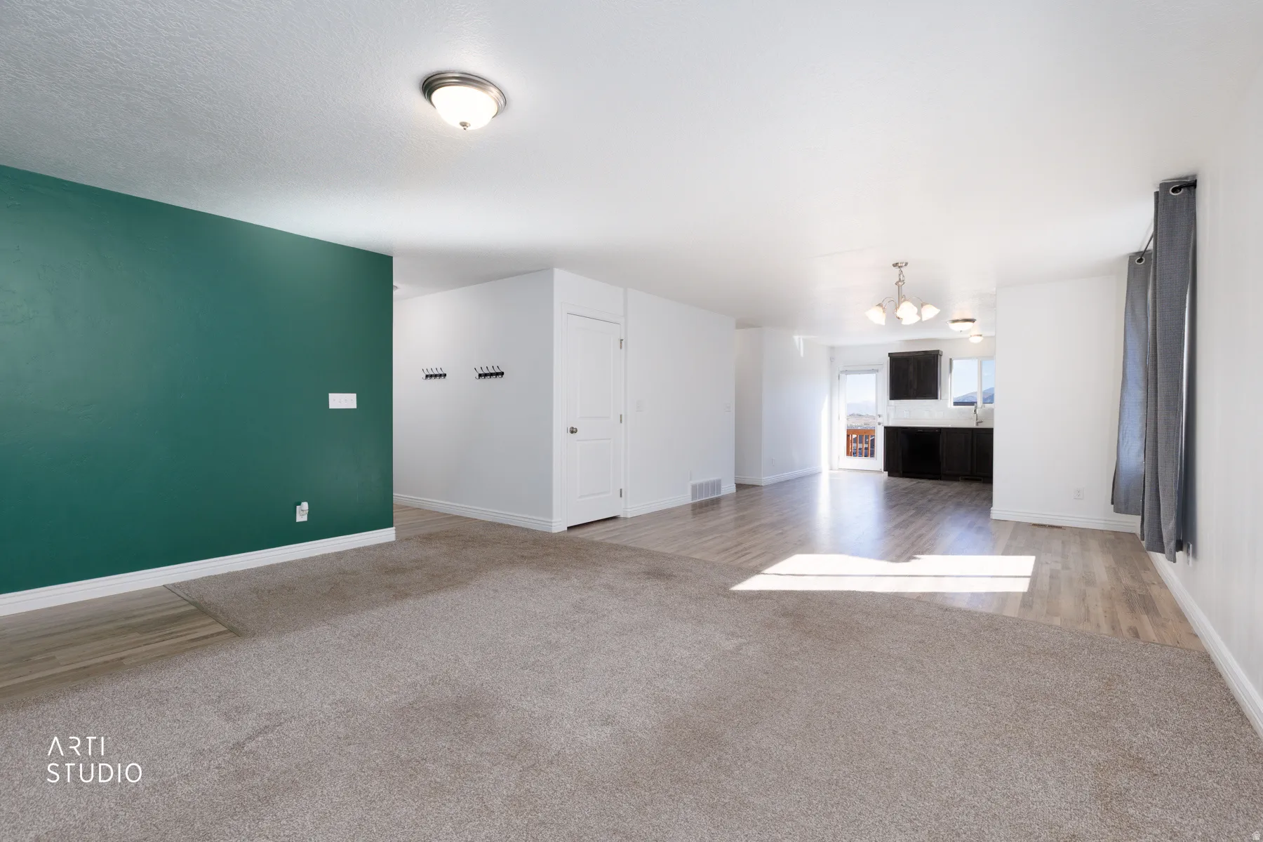 Unfurnished living room with light carpet, a chandelier, and light wood-style floors