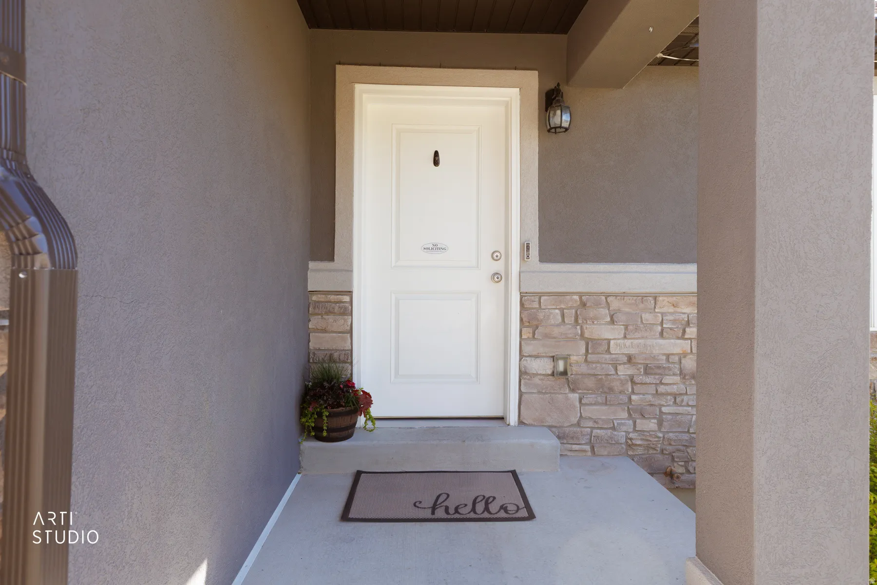 Doorway to property featuring stucco siding and stone siding