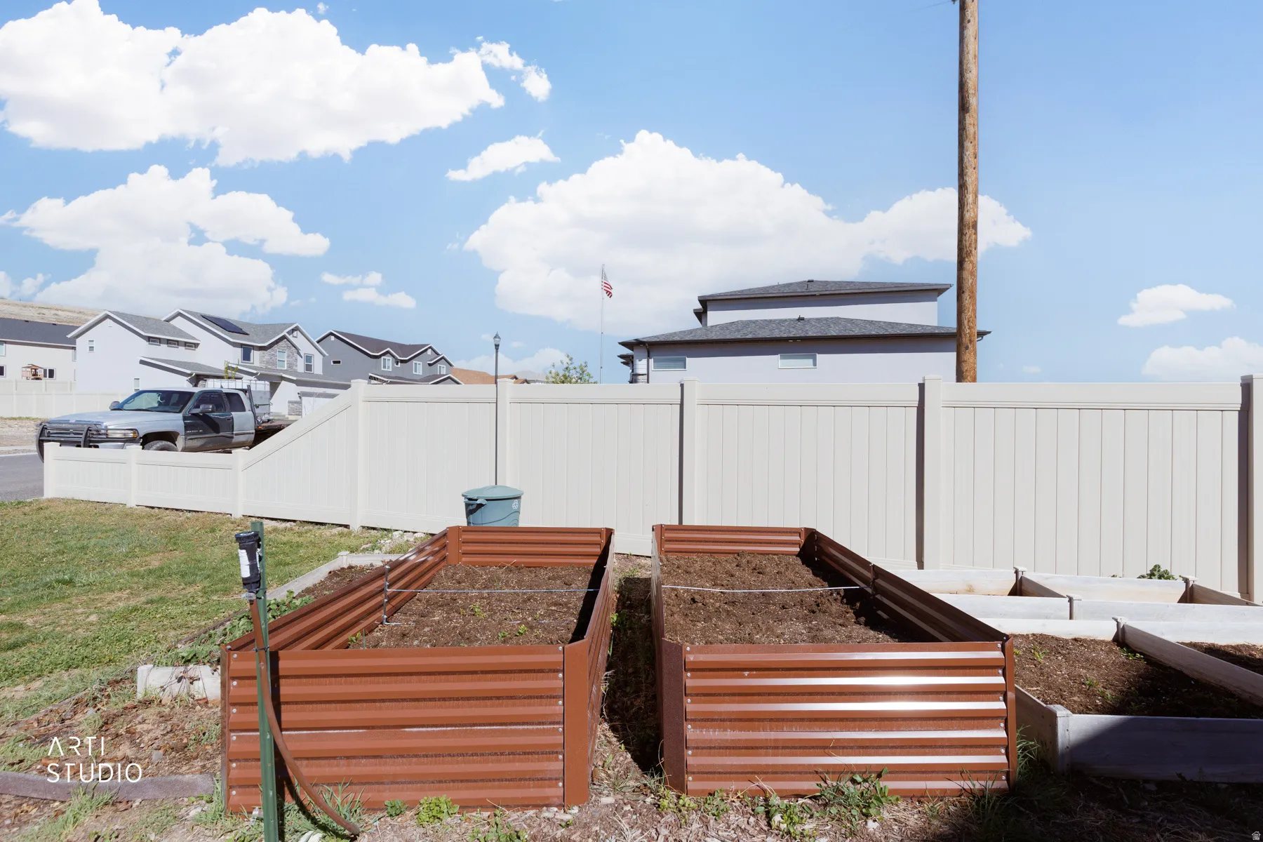 Fenced backyard featuring a garden and a residential view