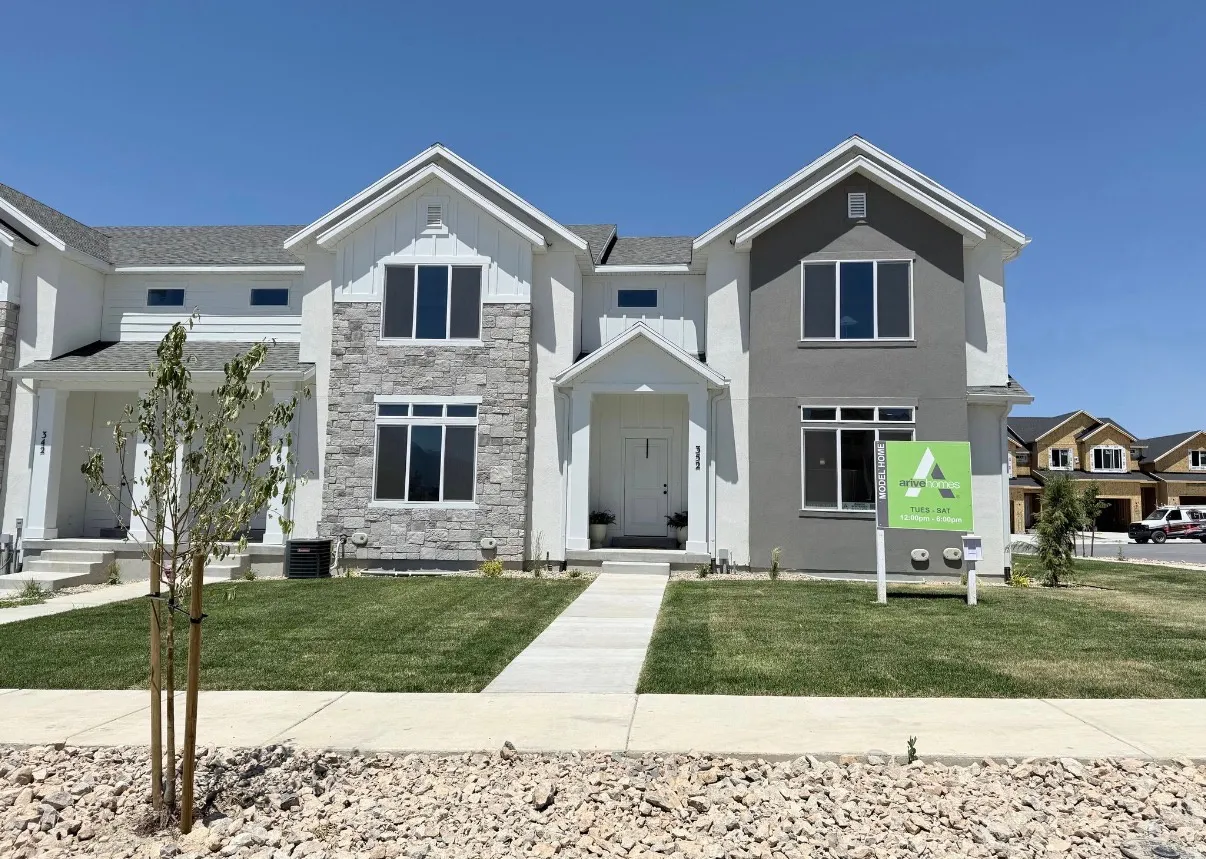 Modern two-story townhome featuring a mixed-material facade with stone veneer and vertical siding accents