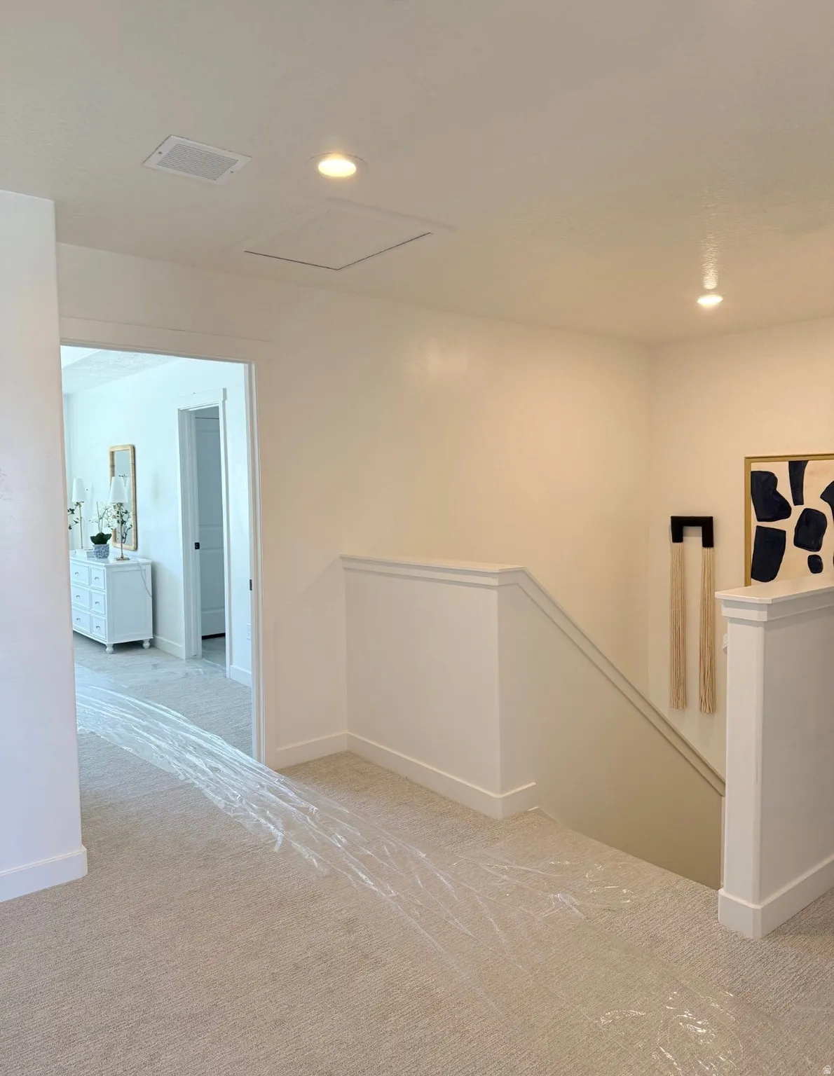 Upper-level landing featuring neutral carpeting, white balustrade, and recessed lighting