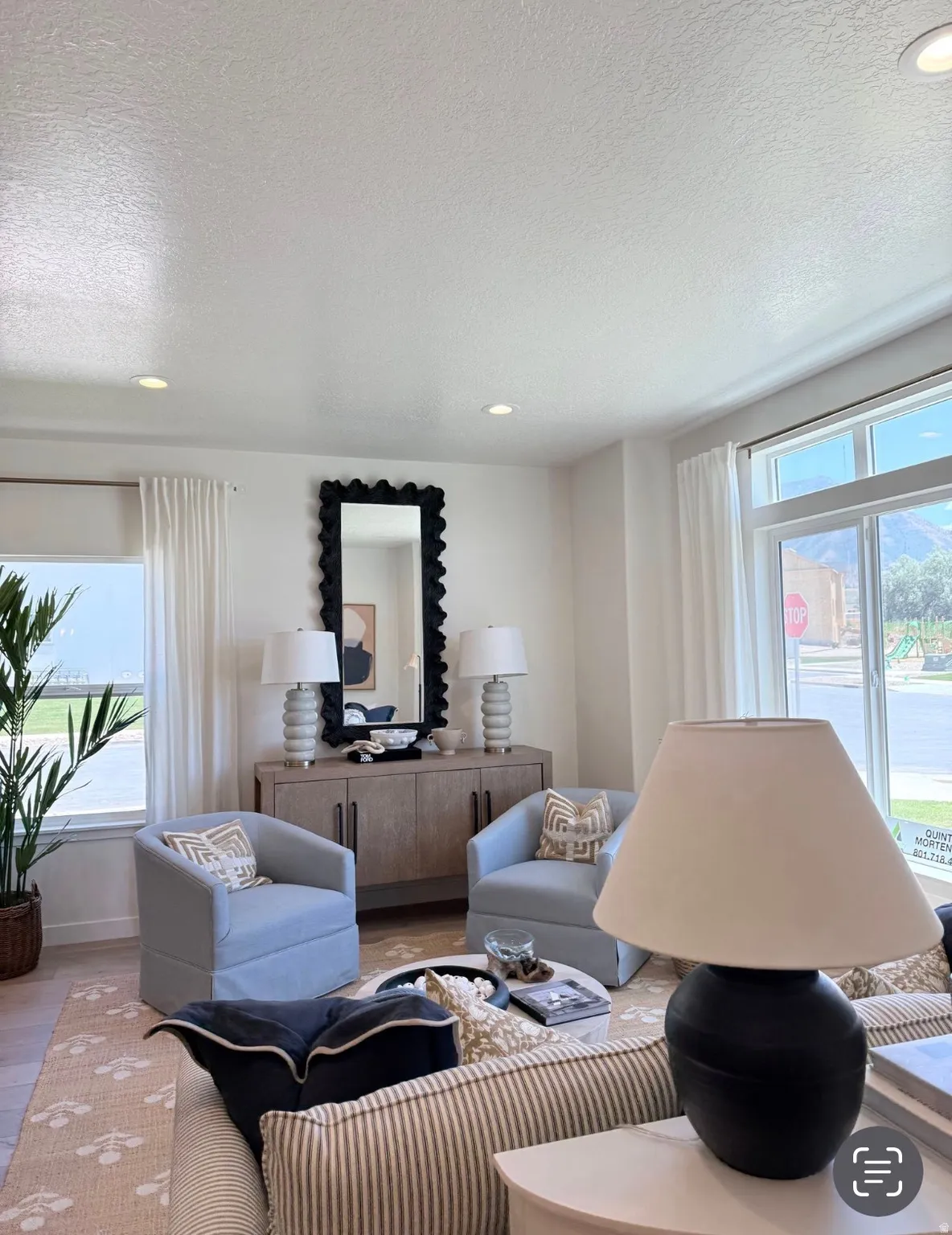 Bright living area featuring recessed lighting, large windows with white trim, and light wood-finish flooring