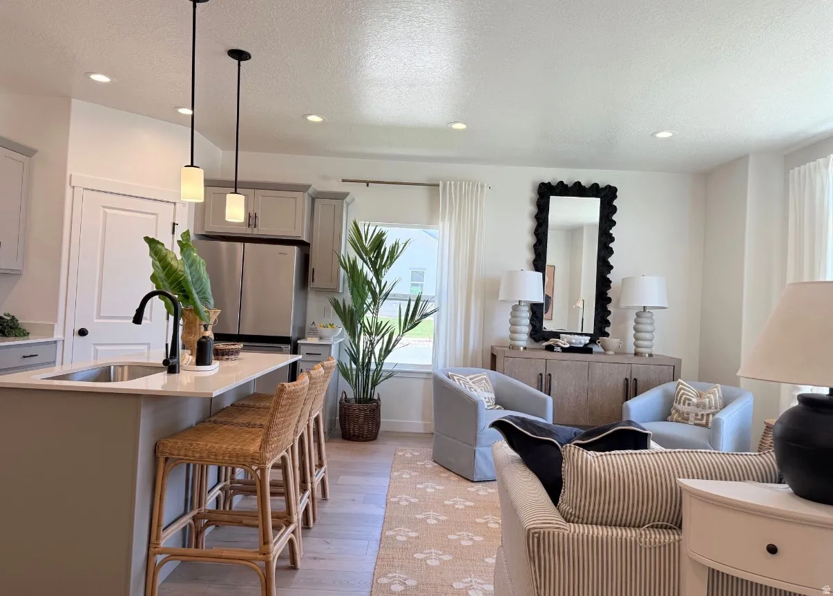 Open-concept living space featuring wood-finish flooring, recessed lighting, and a kitchen island with pendant lights and a stainless steel sink