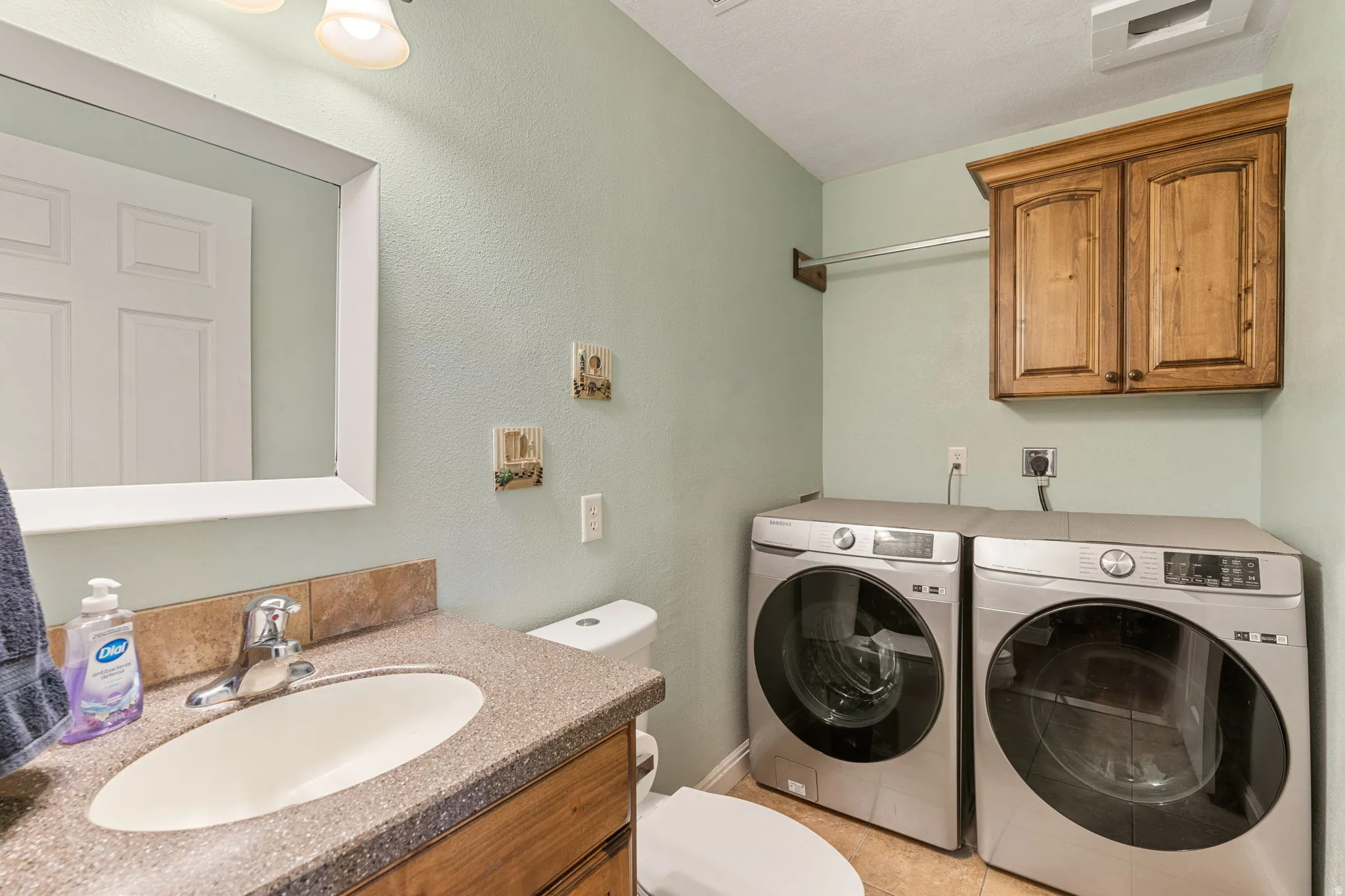 Laundry area with washer and dryer and a textured wall