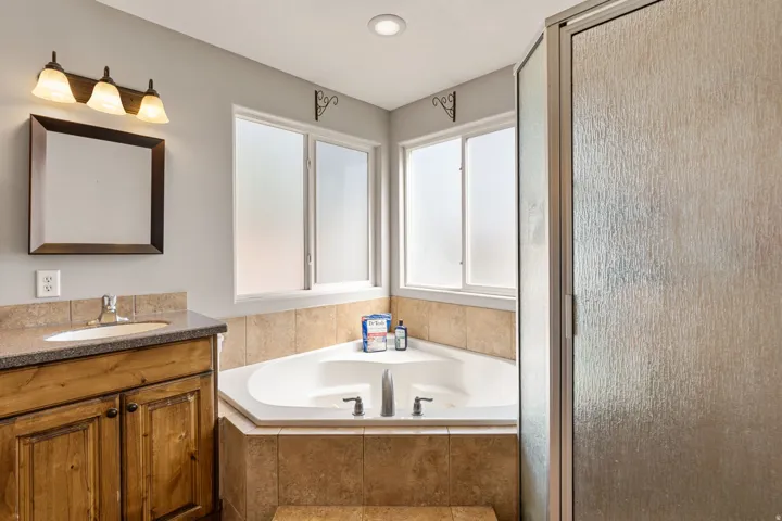 Primary bathroom with vanity, a bath, a stall shower, and recessed lighting