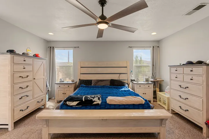 Primary bedroom with light carpet, a ceiling fan, recessed lighting, and a textured ceiling