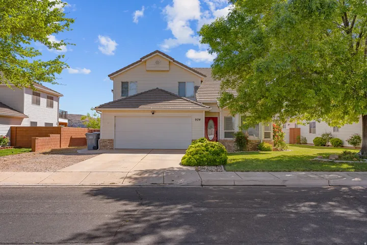 Traditional-style house with a tiled roof, brick siding, driveway, and an attached garage