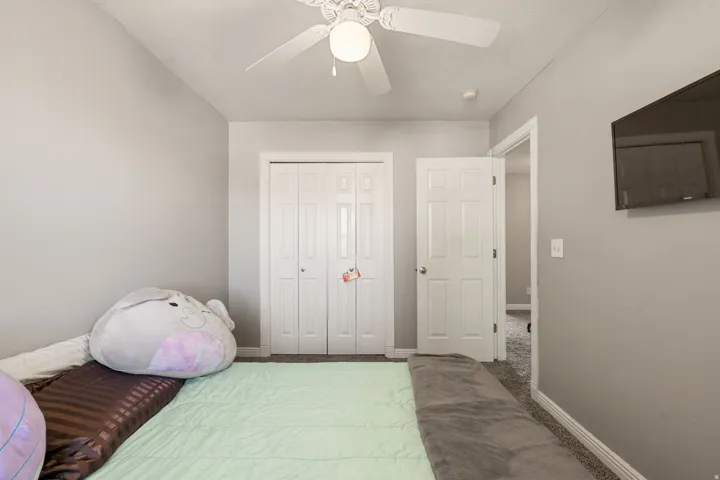 Carpeted bedroom featuring a closet and ceiling fan