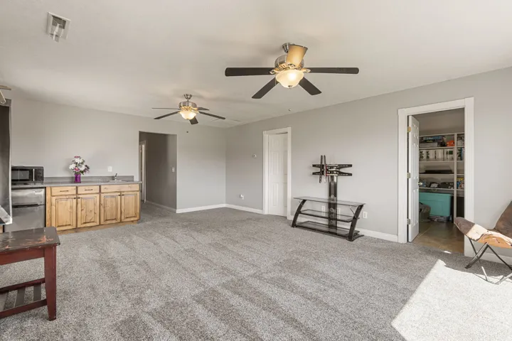 Family room  with light colored carpet and a ceiling fan