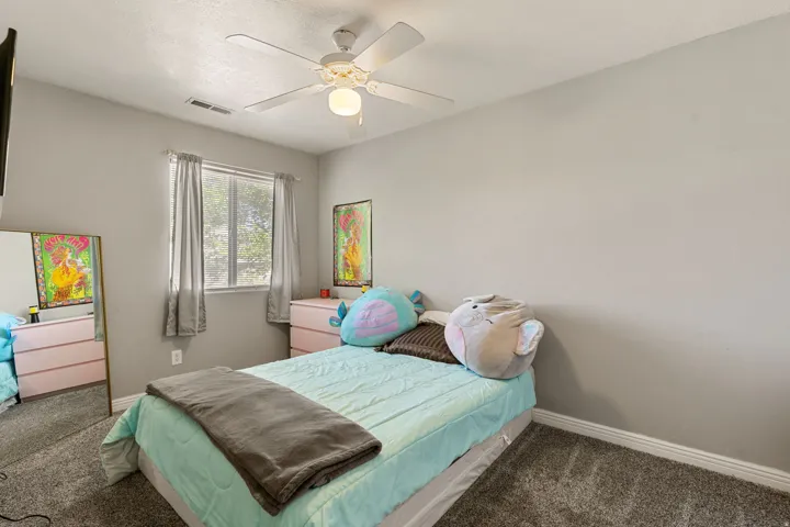 Bedroom with dark colored carpet and a ceiling fan