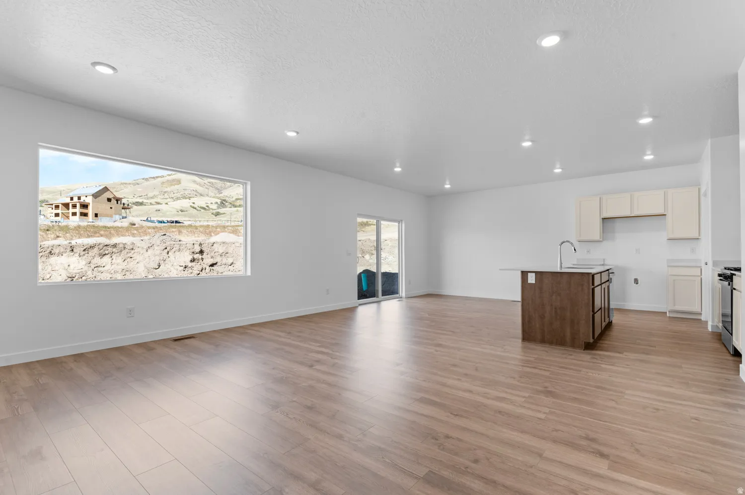Unfurnished living room with light wood-style floors, a textured ceiling, and recessed lighting