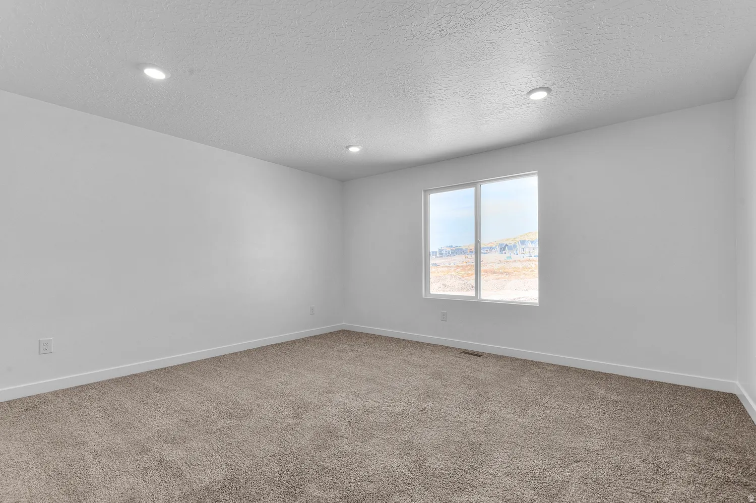 Carpeted spare room with a textured ceiling and recessed lighting
