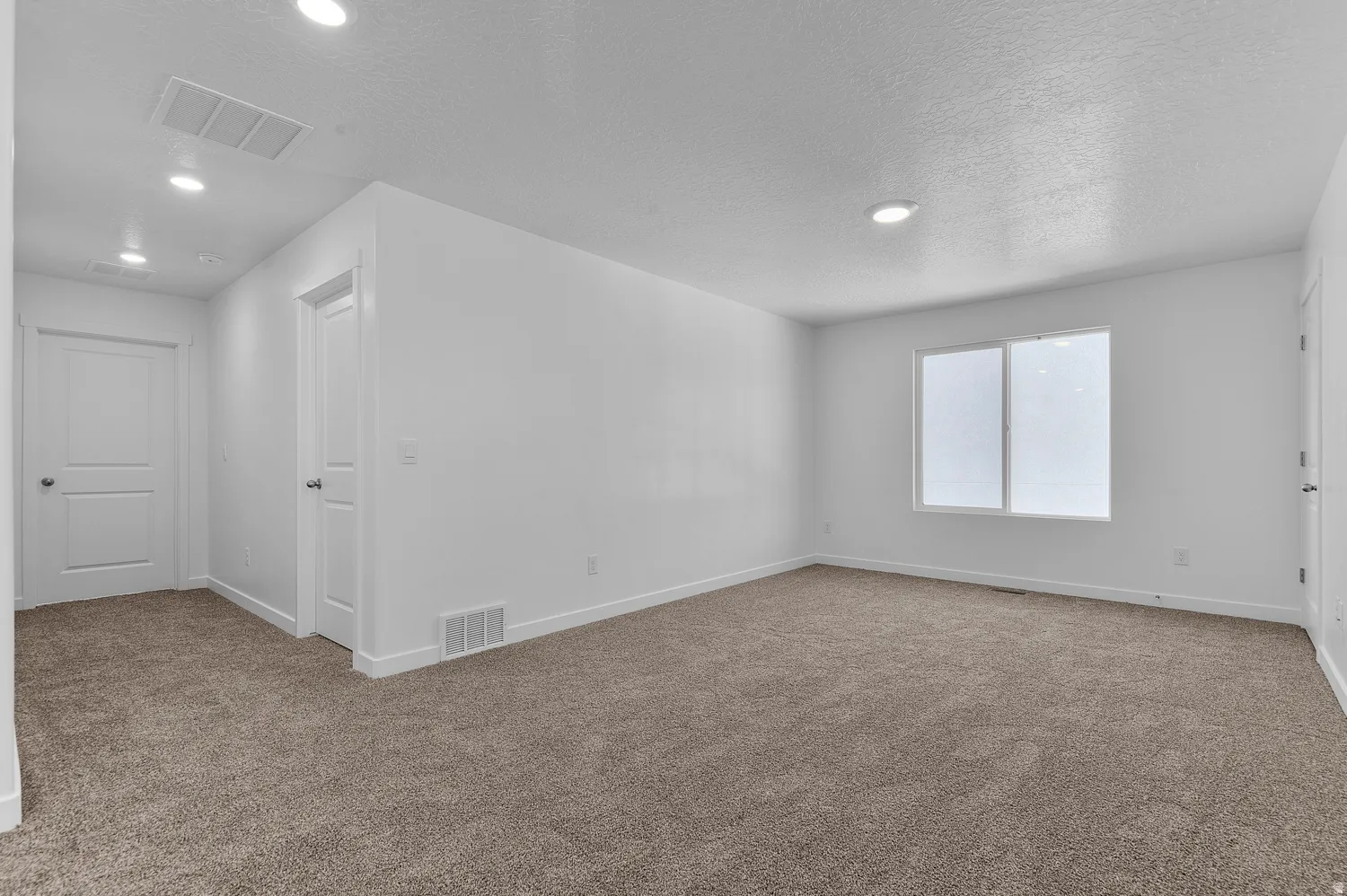Carpeted spare room featuring a textured ceiling and recessed lighting