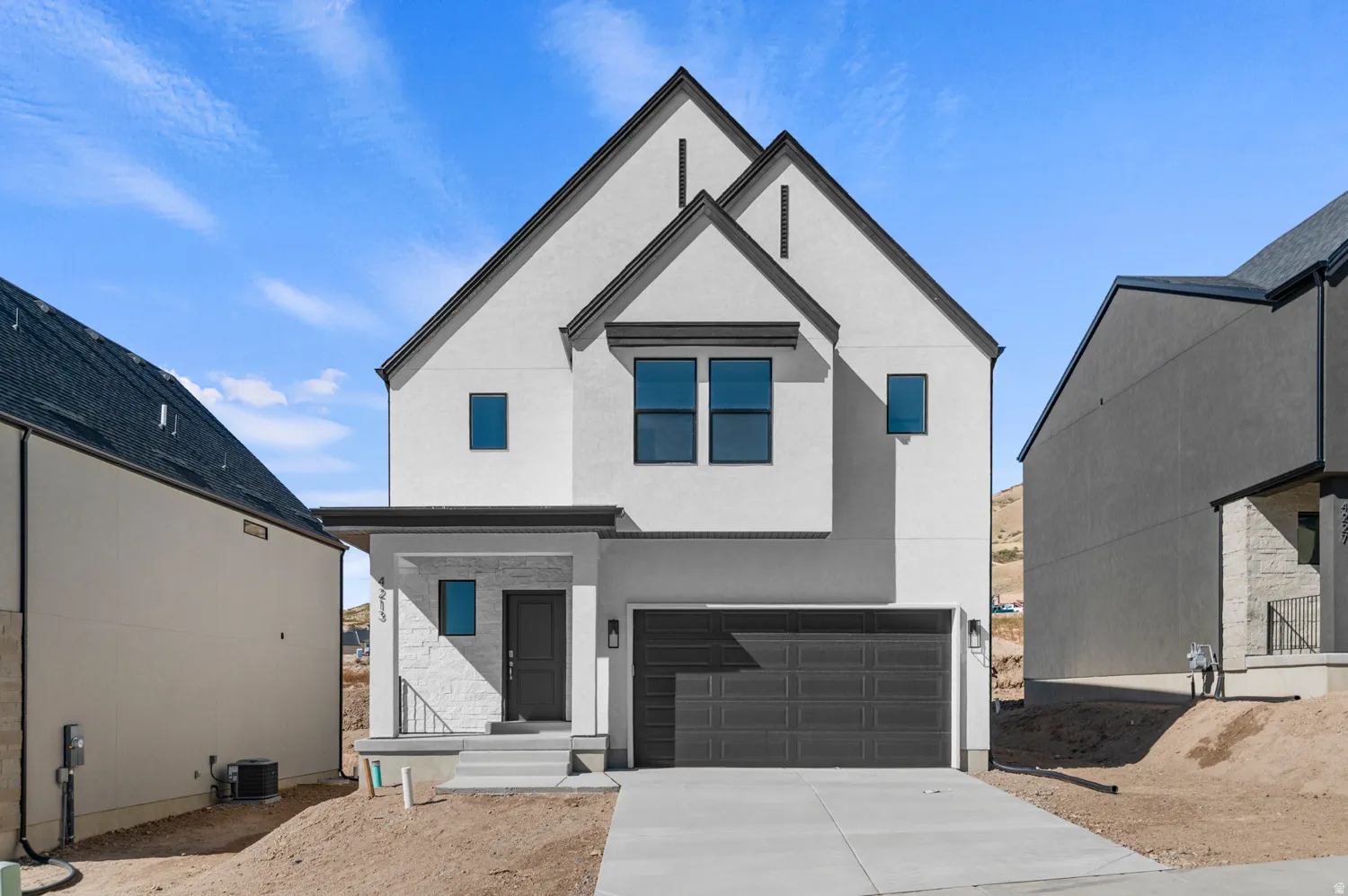 View of front facade featuring an attached garage, driveway, and stucco siding