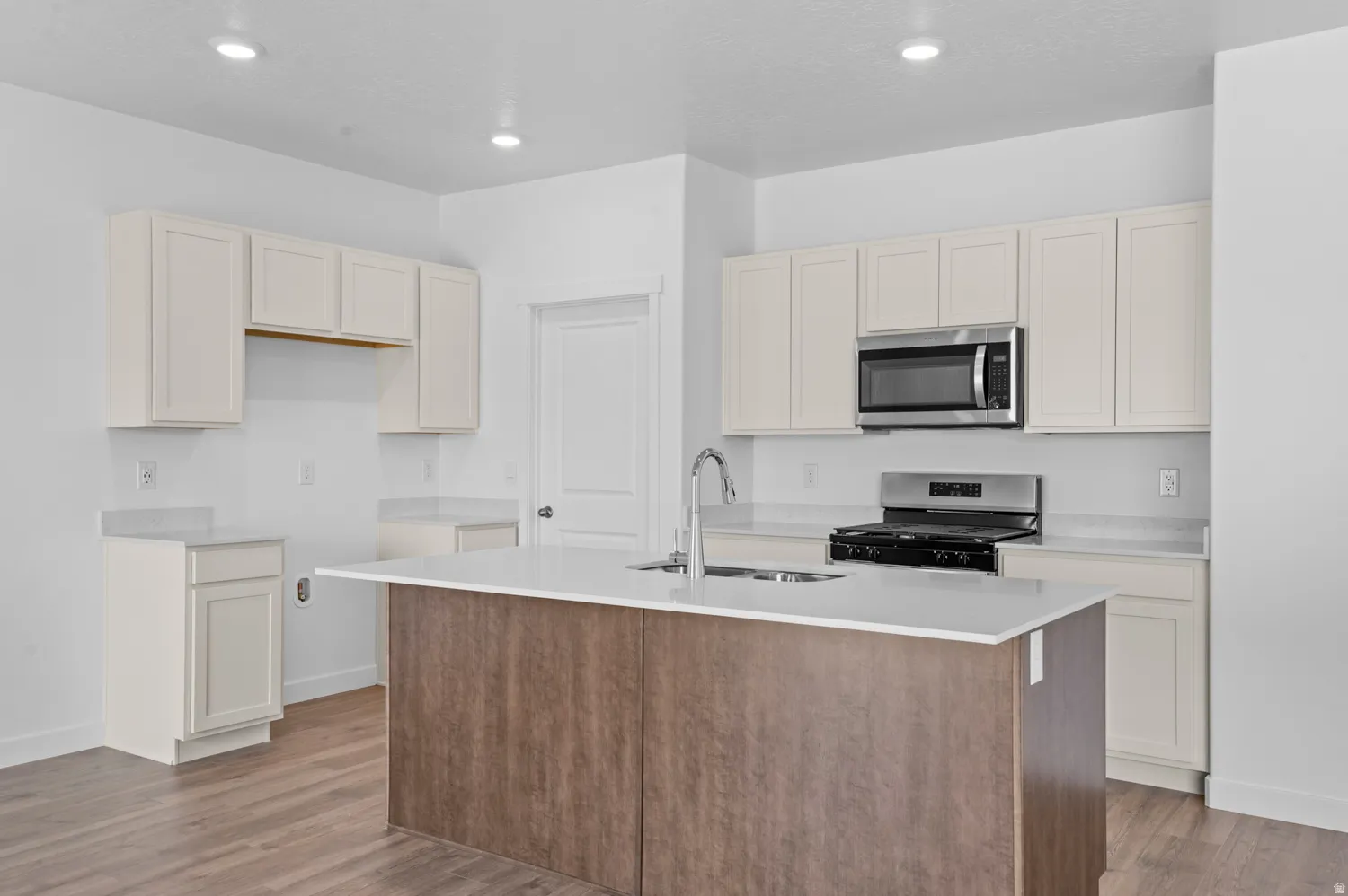 Kitchen featuring a center island with sink, stainless steel appliances, dark wood finished floors, light stone counters, and recessed lighting