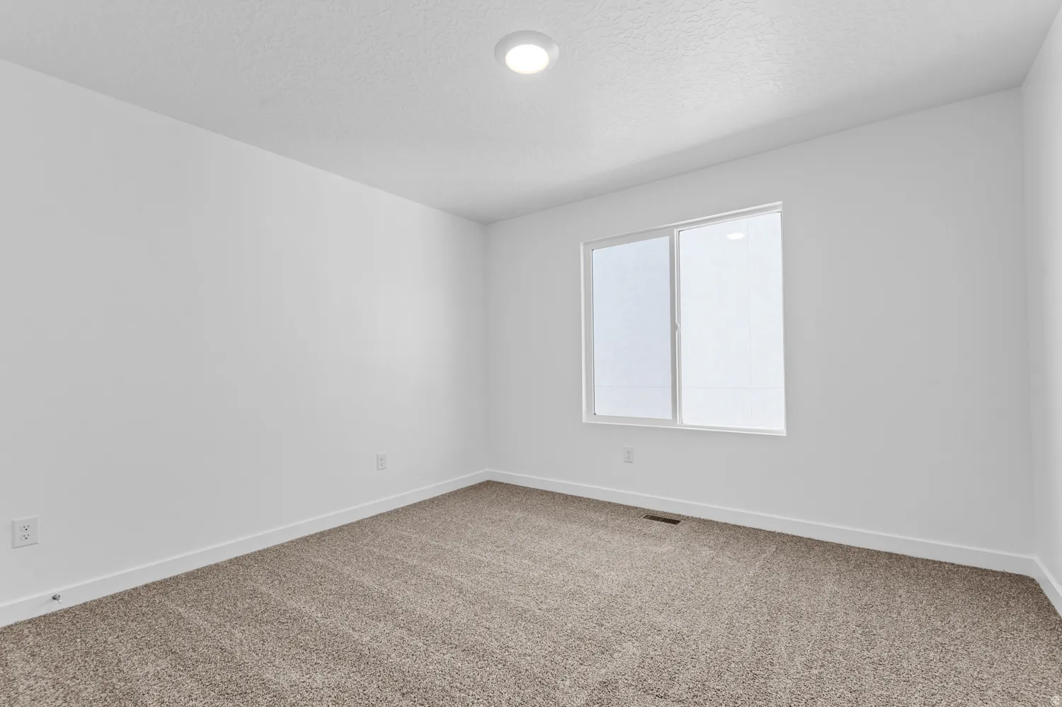 Carpeted empty room with baseboards and a textured ceiling