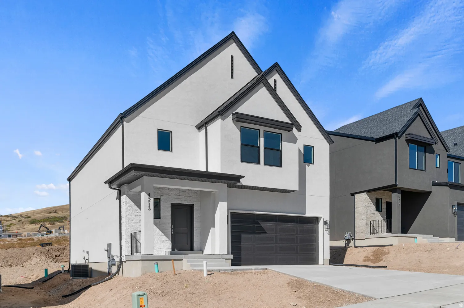 View of front of property featuring a garage, stucco siding, concrete driveway, and stone siding