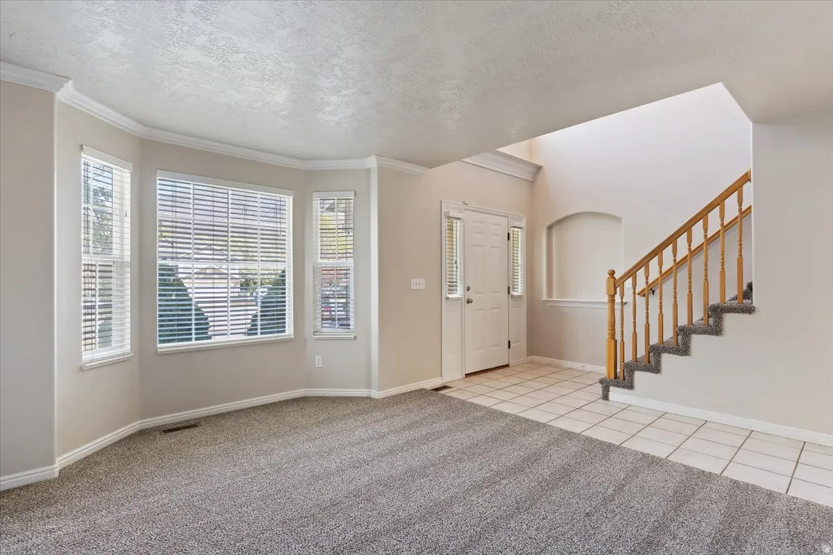 Foyer featuring light colored carpet, a textured ceiling, and light tile patterned floors
