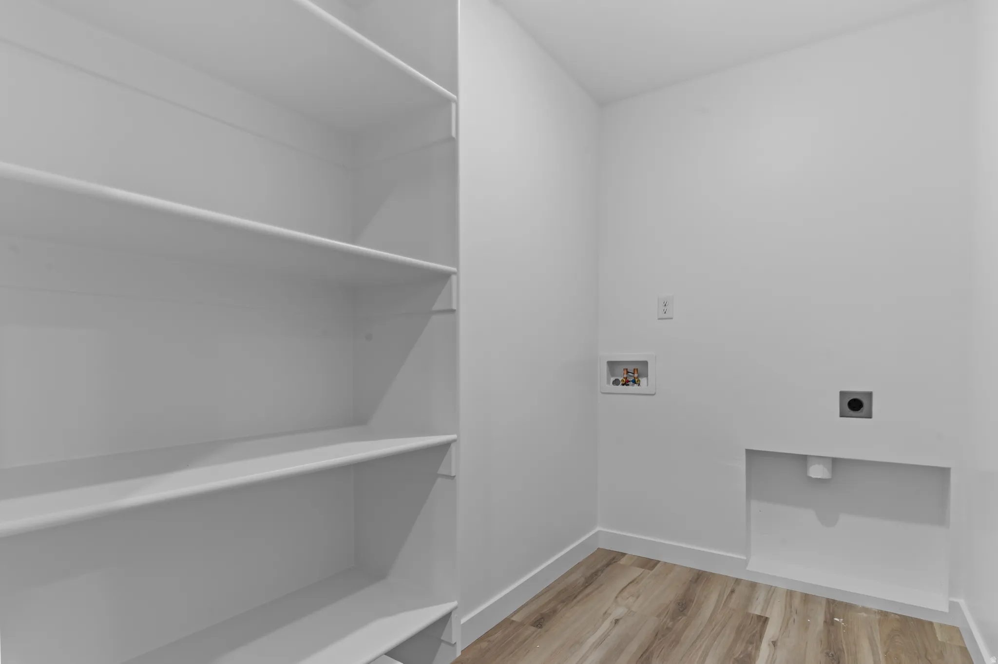 Laundry area featuring washer hookup, light wood finished floors, and hookup for an electric dryer