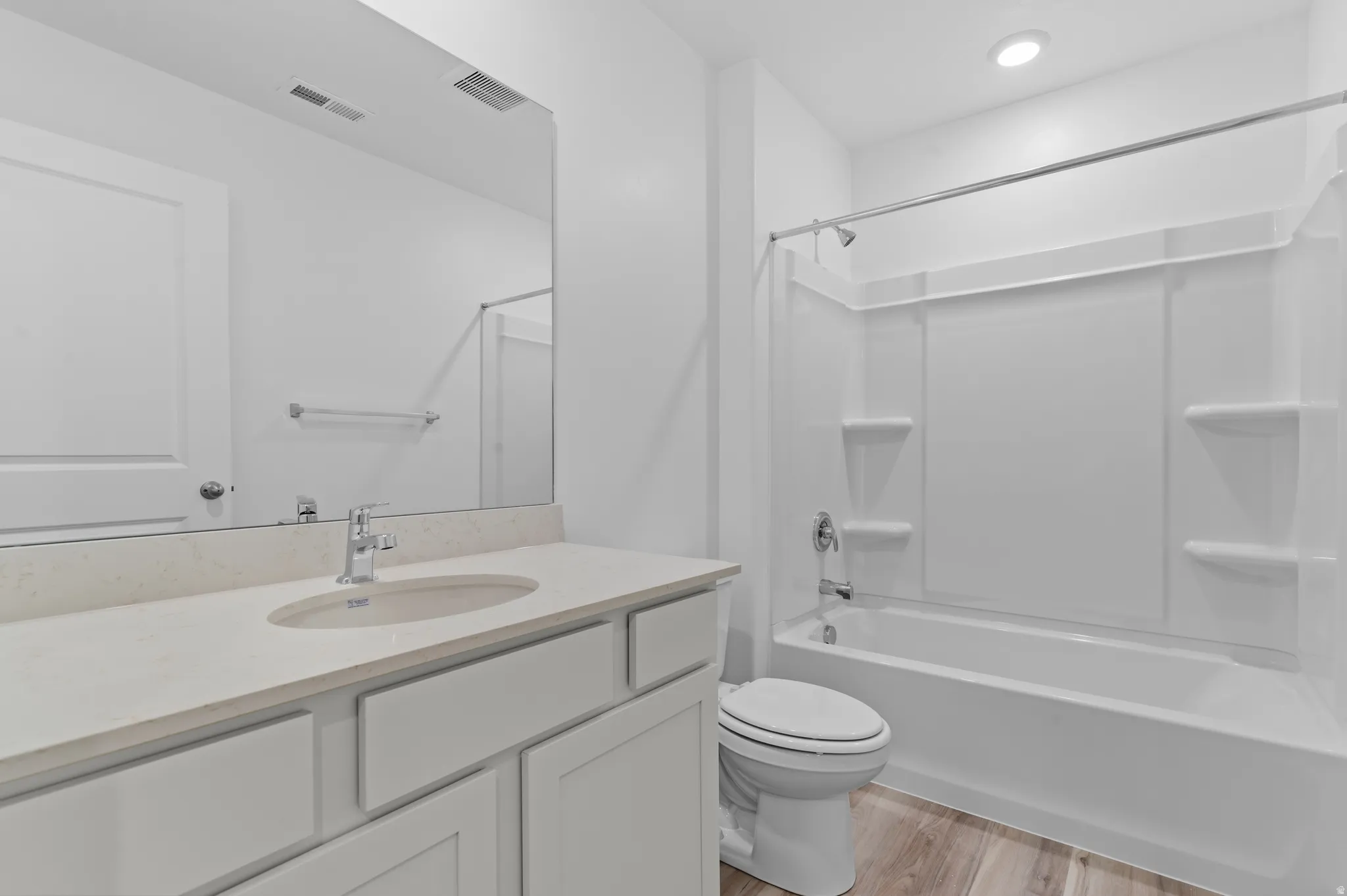 Bathroom with vanity, light wood-style floors, shower / bath combination, and recessed lighting