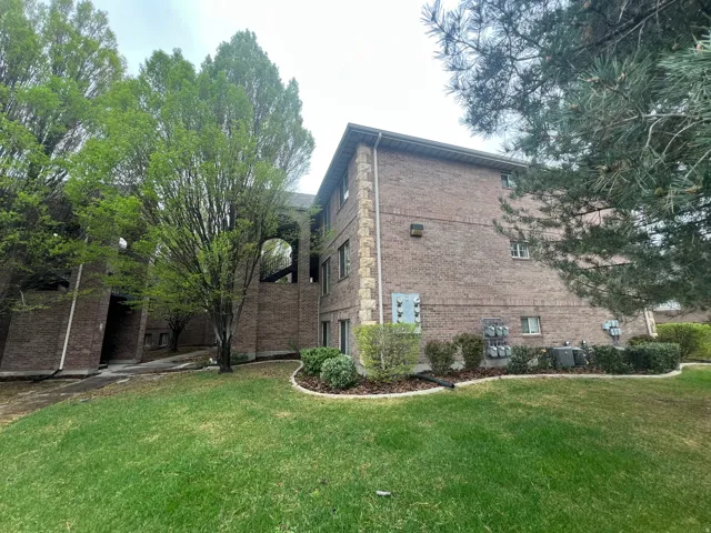 View of property exterior featuring a lawn and brick siding