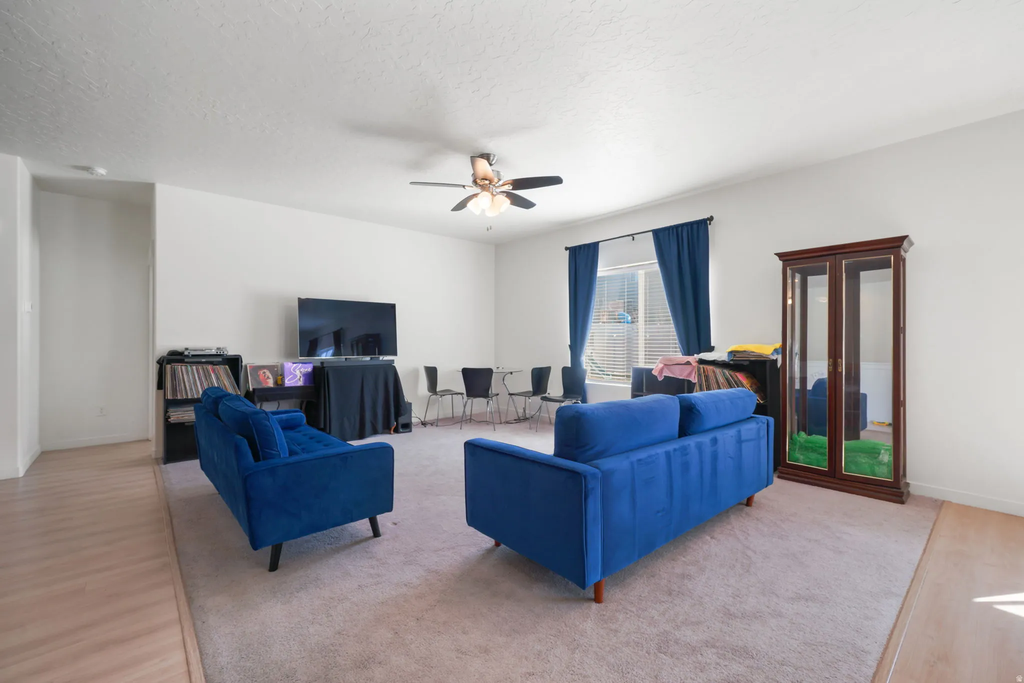 Living area featuring ceiling fan, light wood-type flooring, a textured ceiling, and light colored carpet