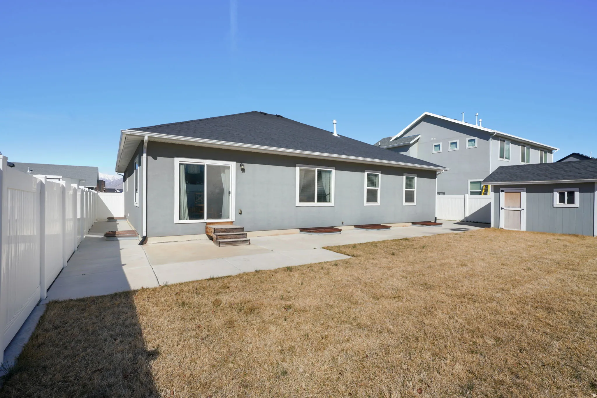 Rear view of house featuring a patio, a fenced backyard, an outdoor structure, entry steps, and roof with shingles